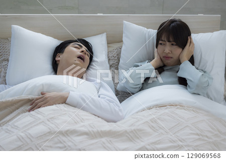 一個年輕人在床上睡覺打呼嚕 一個年輕人在床上睡覺打呼嚕 129069568