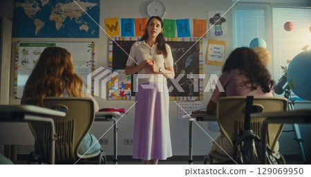 Dolly Shot of Female Teacher Starting Lesson, Teaching Ecology to Primary School Children in Classroom 129069950