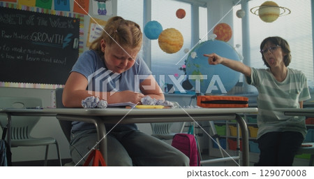 Depressed Primary School Girl Sitting at Desk While Aggressive Classmates Abusing Her 129070008