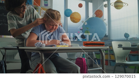 Depressed Primary School Girl Sitting at Desk While Aggressive Classmates Abusing Her Depressed Primary School Girl Sitting at Desk While Aggressive Classmates Abusing Her 129070015