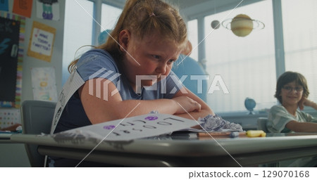 Upset Elementary School Girl Crying While Classmates Bullying Her, Laughing and Throwing Papers Upset Elementary School Girl Crying While Classmates Bullying Her, Laughing and Throwing Papers 129070168