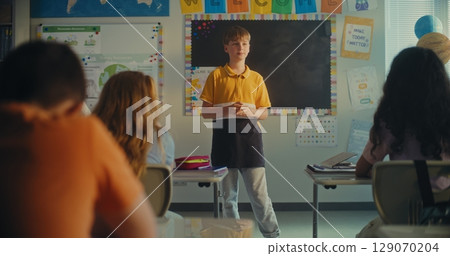 Female Teacher Calling Elementary School Student to the Board. Talented Boy Presenting Homework 129070204