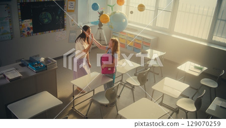 End of the School Day: Female Teacher Helping the Girl to Pack Her School Supplies 129070259