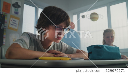 Sad Elementary School Student Sitting Alone and Crying While Classmates Bullying Him 129070271