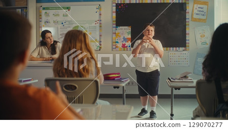 Elementary School Boy Presenting Homework on Ecology in Front of Classmates and Female Teacher 129070277