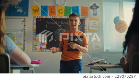 Primary School Boy with Digital Tablet Showcasing Knowledge of Renewable Energy in Front of Class Primary School Boy with Digital Tablet Showcasing Knowledge of Renewable Energy in Front of Class 129070287