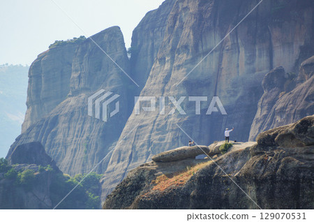 A man taking a commemorative photo on top of the rock formations of Meteora 129070531