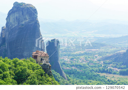 A strange rock formation jutting into the sky and a nearby monastery 129070542