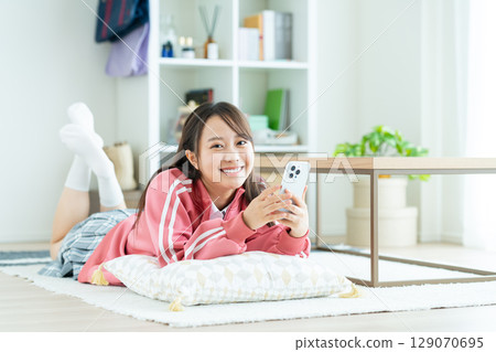 A high school girl looking at her smartphone in her room 129070695