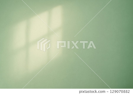 The shadow of the window reflected on the green wall and soft natural light 129070882