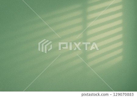Light and shadow through the blinds on a green wall 129070883