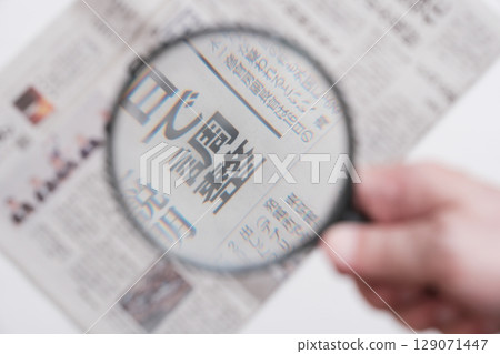 Newspaper viewed through a magnifying glass 129071447