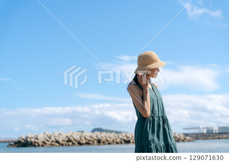 夏天，一位穿著裙子的女人站在海灘上 129071630