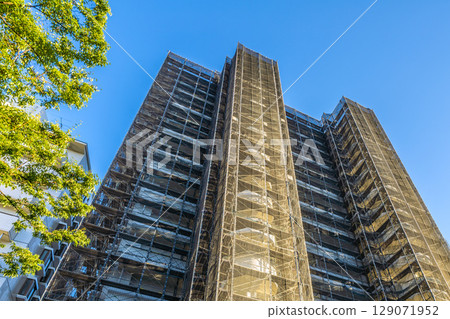 日本橫濱城市景觀，午後的陽光......公寓大樓維修和檢查的鷹架和防護網的景色=7月29日 129071952