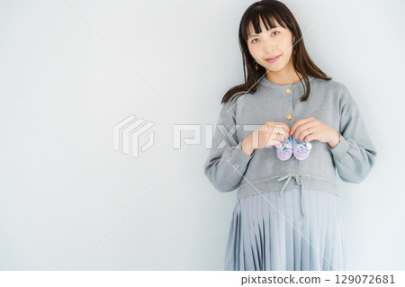 一位即將分娩的孕婦手裡拿著手工編織的嬰兒鞋 一位即將分娩的孕婦手裡拿著手工編織的嬰兒鞋 129072681