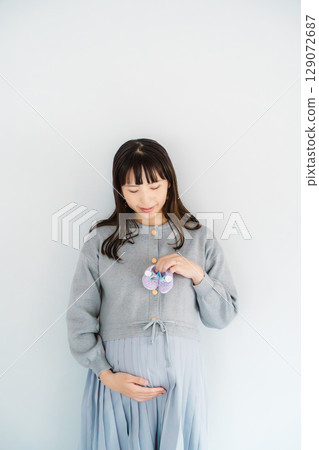 A pregnant woman about to give birth holding hand-knitted baby shoes A pregnant woman about to give birth holding hand-knitted baby shoes 129072687