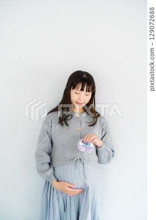 A pregnant woman about to give birth holding hand-knitted baby shoes A pregnant woman about to give birth holding hand-knitted baby shoes 129072688