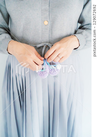 A pregnant woman about to give birth holding hand-knitted baby shoes A pregnant woman about to give birth holding hand-knitted baby shoes 129072692