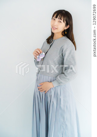 A pregnant woman about to give birth holding hand-knitted baby shoes A pregnant woman about to give birth holding hand-knitted baby shoes 129072699