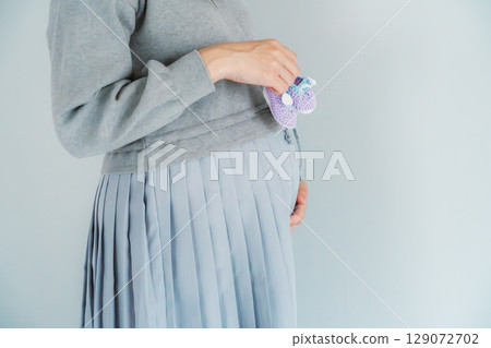 A pregnant woman about to give birth holding hand-knitted baby shoes A pregnant woman about to give birth holding hand-knitted baby shoes 129072702
