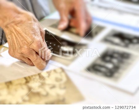 Elderly woman's hand holding an old black-and-white photograph Elderly woman's hand holding an old black-and-white photograph 129072734