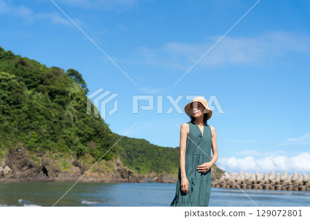 夏天，一位穿著裙子的女人站在海灘上 129072801