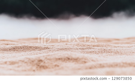 Soft sand stretches along the shore against a misty background by a calm water body 129073850