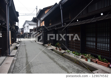 Spring in Gifu Prefecture, Japan: Old streets in the center of Takayama city, historic Japanese houses and beautiful potted plants on the roadside Spring in Gifu Prefecture, Japan: Old streets in the center of Takayama city, historic Japanese houses and beautiful potted plants on the roadside 129074582