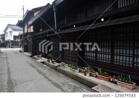 Spring in Gifu Prefecture, Japan: Old streets in the center of Takayama city, historic Japanese houses and beautiful potted plants on the roadside Spring in Gifu Prefecture, Japan: Old streets in the center of Takayama city, historic Japanese houses and beautiful potted plants on the roadside 129074583