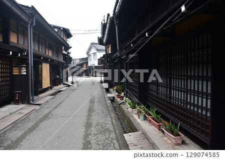 Spring in Gifu Prefecture, Japan: Old streets in the center of Takayama city, historic Japanese houses and beautiful potted plants on the roadside Spring in Gifu Prefecture, Japan: Old streets in the center of Takayama city, historic Japanese houses and beautiful potted plants on the roadside 129074585