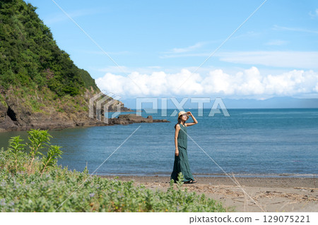 一位穿著裙子的女人沿著海灘散步 129075221