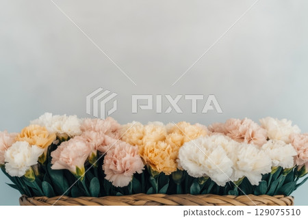 Soft pastel flowers arranged in a woven basket on a simple background Soft pastel flowers arranged in a woven basket on a simple background 129075510