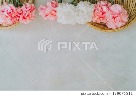 Beautiful arrangement of pink and white carnations in woven baskets on a light background Beautiful arrangement of pink and white carnations in woven baskets on a light background 129075511