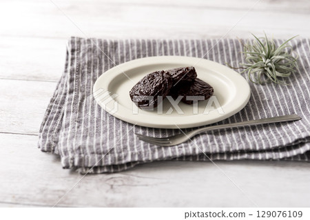 3 dried prunes on linen + fork + air plant 129076109