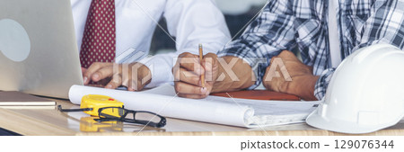 Banner Contractor construction engineer meeting on architect table at construction site. Businessman engineer manager discuss talk together foreman team builder using measure tape with copy space 129076344