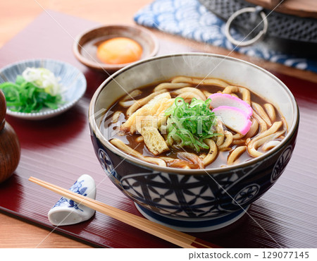 Hot curry udon topped with chopped fried tofu and kamaboko 129077145