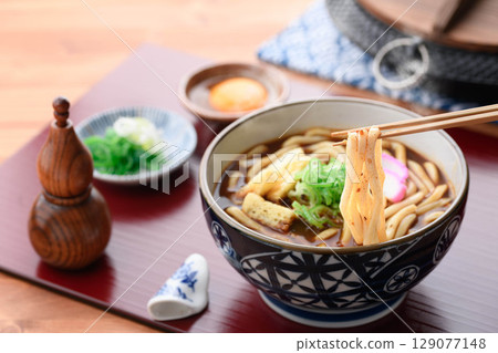 Hot curry udon topped with chopped fried tofu and kamaboko Hot curry udon topped with chopped fried tofu and kamaboko 129077148