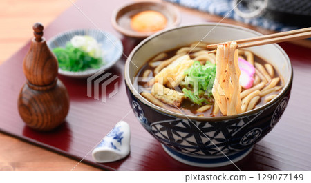 Hot curry udon topped with chopped fried tofu and kamaboko 129077149