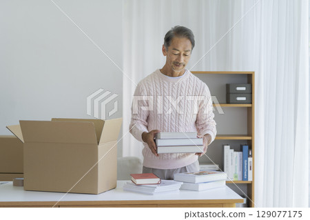 老人把書放進紙箱。圖片為搬家和整理。 129077175