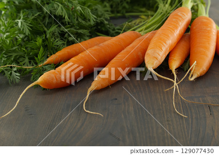 Fresh Organic Carrots with Tops on Wooden Background Fresh Organic Carrots with Tops on Wooden Background 129077430