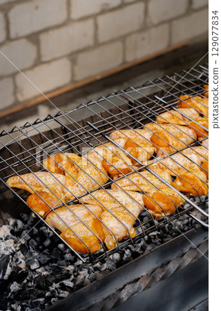 BBQ picnic time Roasted chicken legs and wings on grill. Grilling meat on outdoor grill grid tasty barbeque chicken steak with smoke flames juicy meat in the backyard 129077834