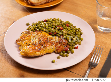 Appetizing crispy chicken with peas as side dish on plate 129077880