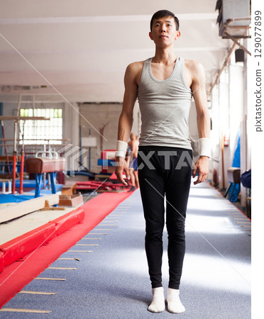 Gymnast stands on the track after performing an exercise on sports equipment 129077899