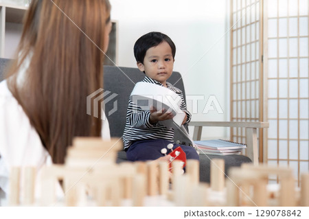 Focused child holding ukulele, engaging in music play Focused child holding ukulele, engaging in music play 129078842