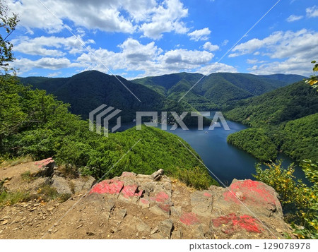 View from Piatra lui Lucaci over the Tarnita lake and forest mountains on a beautiful summer day with blue sky and white clouds. Cluj, Romania 129078978