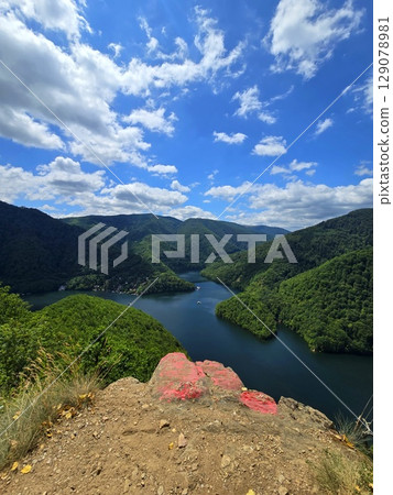 View from Piatra lui Lucaci over the Tarnita lake on a beautiful sunny summer day with blue sky and white clouds; red stone in foreground. Cluj, Romania View from Piatra lui Lucaci over the Tarnita lake on a beautiful sunny summer day with blue sky and white clouds; red stone in foreground. Cluj, Romania 129078981