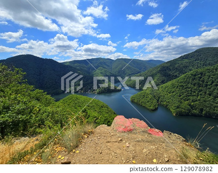 View from Piatra lui Lucaci over the Tarnita lake and forest mountains on a beautiful summer day with blue sky and white clouds. Cluj, Romania 129078982