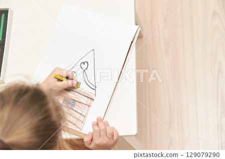 Young caucasian child drawing with colorful crayons on paper at home creating 129079290