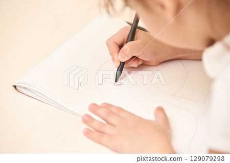Child drawing with pencil on sketchbook, close up of hands and artwork in soft 129079298