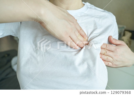 Female adjusting white t shirt fit on chest with hands indoors Female adjusting white t shirt fit on chest with hands indoors 129079368